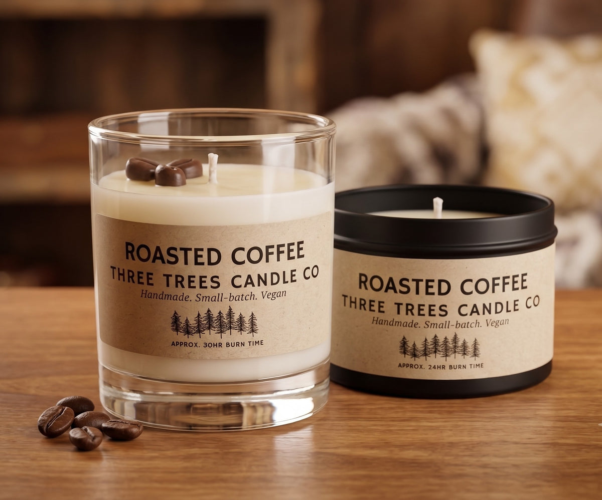 Three Trees Candle Co. Roasted Coffee scented candles in a glass jar and black tin on a cozy wooden table with scattered coffee beans